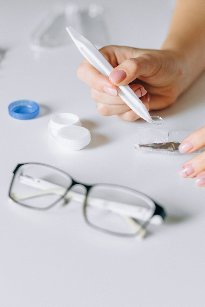 photo of woman picking up contact from case with glasses